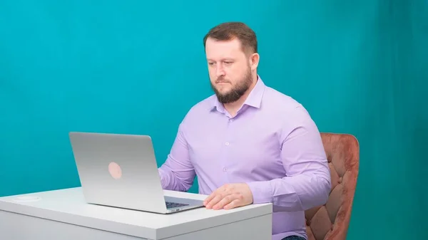 Jovem homem de negócios feliz está digitando no laptop na tela verde. Retrato de um homem que fala a olhar para o portátil. Homem trabalhando em sua mesa no escritório . — Fotografia de Stock