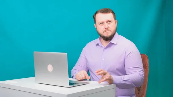 Young happy businessman holds a conference meeting at a laptop, a man is nervous and worried, on a green screen. Portrait of a male talking man looking into his laptop. Man working at his desk in the — Stock Photo, Image