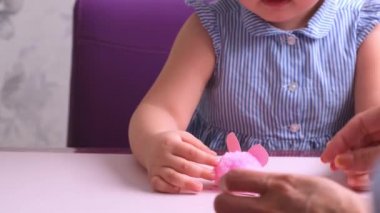 Küçük kız, annesiyle birlikte yumuşak, pembe bir domuz yapar. Her gün anneler, çocuklarla el işi yapar..