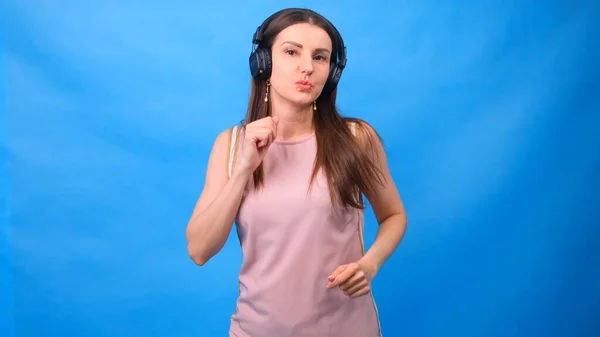 Schöne Energy Girl mit Kopfhörer Musik hören auf blauem Hintergrund im Studio — Stockfoto