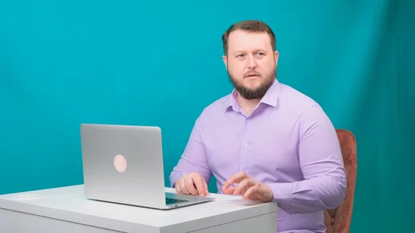 若い幸せなビジネスマンは、ノートパソコンで会議を開催し、男は緊張しており、緑の画面上で、心配しています。ノートパソコンを覗き込む男の肖像画。机の上で働いてる男が — ストック写真