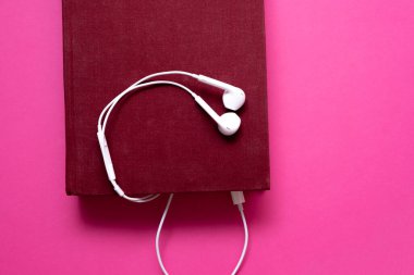 Pembe arka planda izole edilmiş kulaklıklı ses kitabı