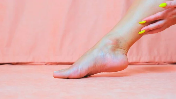 Kobieca noga blisko. Kobieta głaszcze miękką skórę stopy. Ręka pięknej i eleganckiej zadbanej dziewczyny dotykającej jej nogi. Spa, peeling i pielęgnacja stóp. — Zdjęcie stockowe
