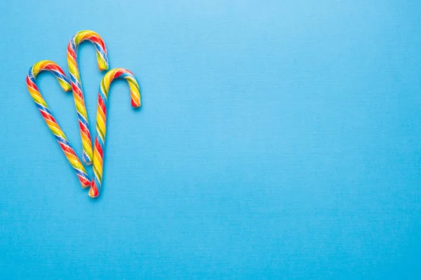 Multi-colored candy canes on a blue background, copy space — Stock Photo, Image