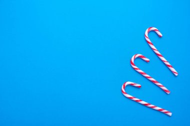 Mavi arkaplanda beyaz ve kırmızı baston şekerler, kopyalama alanı