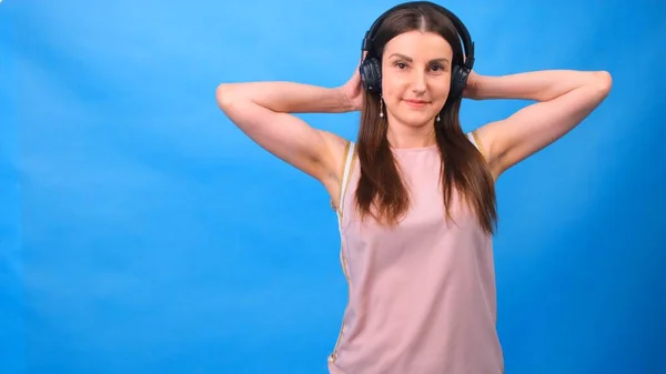Beautiful Energy Girl med hörlurar lyssnar på musik på en blå bakgrund i studion — Stockfoto