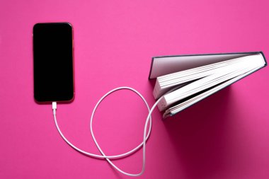 Akıllı telefon eski kitaba bir kabloyla bağlı ve oradan bilgi indiriyor.