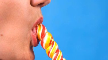 Lolipopu olan seksi esmer kadın mavi arka planda izole edilmiş..