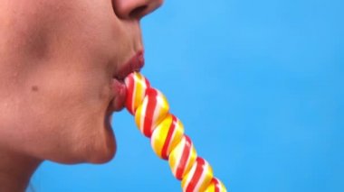 Lolipopu olan seksi esmer kadın mavi arka planda izole edilmiş..