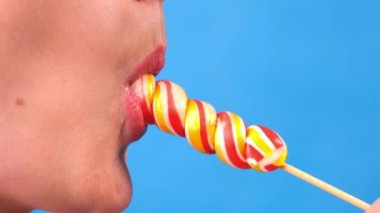 Lolipopu olan seksi esmer kadın mavi arka planda izole edilmiş..