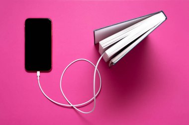 Akıllı telefon eski kitaba bir kabloyla bağlı ve oradan bilgi indiriyor.