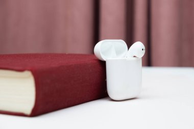 Fotokopi alanı olan eski bir kitaptaki kablosuz kulaklıklar, sesli kitap konsepti, kendi kendine çalışma.