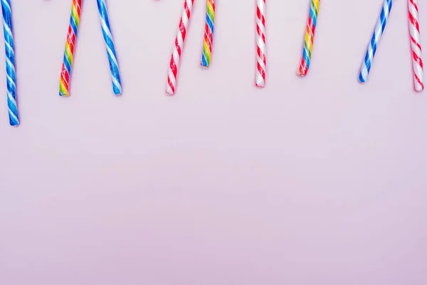 Lot of multi-colored candy canes on a pink background, copy space — Stock Photo, Image