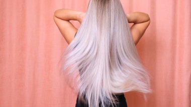 Güzel sarışın kadın uzun dalgalı saçlarını savuruyor. Saç bakımı konsepti.