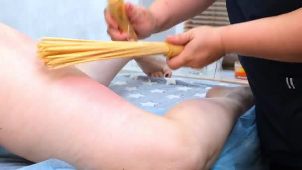 Massagetherapeutin massiert einer dicken Frau auf einem Massagetisch in einem Wellnessbereich mit einem Bambusstab die Beine gegen Cellulite. Spa-Behandlungen. Gesundheit und Schönheit, Ernährung — Stockvideo
