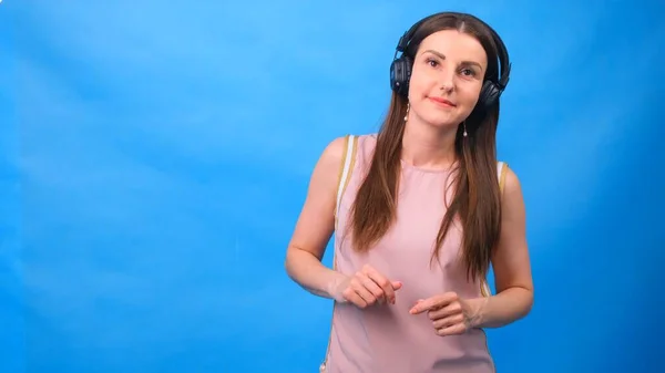 Belle Energy Girl avec écouteurs écoutant de la musique sur un fond bleu dans le studio — Photo