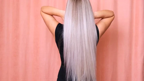 Beautiful female luxurious long straight blond hair. Dyed wavy white blond hair background, dyeing, extensions, treatment, treatment concept. Hair care.