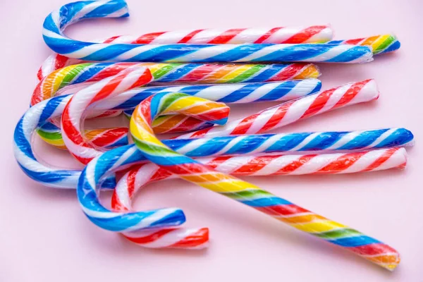 Lot of multi-colored candy canes on a pink background, copy space — Stock Photo, Image