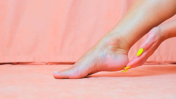 Kobieca noga blisko. Kobieta głaszcze miękką skórę stopy. Ręka pięknej i eleganckiej zadbanej dziewczyny dotykającej jej nogi. Spa, peeling i pielęgnacja stóp. — Zdjęcie stockowe