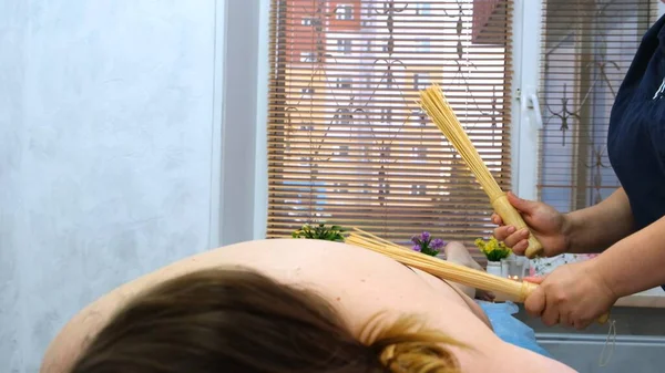 Anti-cellulitis massage met bamboe sticks voor een dikke vrouw. Agressieve strijd tegen vet. Kuuroord. — Stockfoto