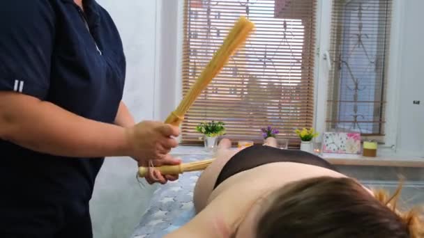 Masaj terapisti, masaj masasındaki şişman bir kadına bambu çubuğuyla anti-selülit ayak masajı yapıyor. Spa tedavileri. Sağlık ve güzellik, diyet — Stok video
