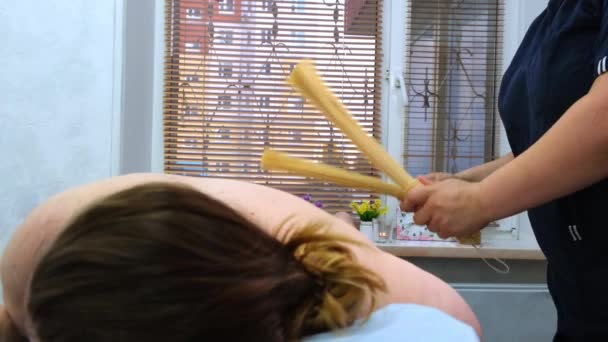 Anti-cellulitis massage met bamboe sticks voor een dikke vrouw. Agressieve strijd tegen vet. Kuuroord. — Stockvideo