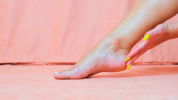 Vrouw streelt de zachte huid van de voet. De hand van een mooi en elegant meisje dat haar been aanraakt. Spa, scrub en voetverzorging. — Stockfoto
