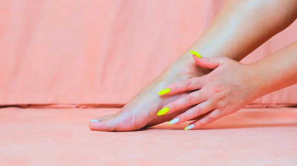 Samica głaszcze miękką skórę stopy. Dłoń pięknej i eleganckiej zadbanej dziewczyny dotykającej jej nogi. Spa, peeling i pielęgnacja stóp. — Zdjęcie stockowe