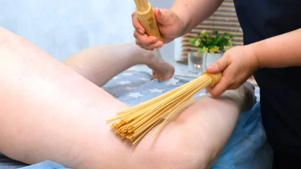 Anti-cellulitis massage met bamboe sticks voor een dikke vrouw. Agressieve strijd tegen vet. Kuuroord. — Stockfoto
