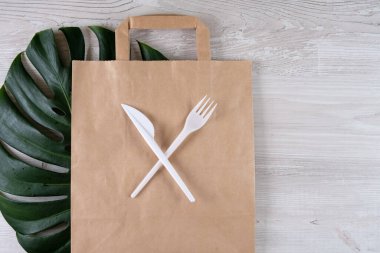 Plastik çatal, kağıt torbada bıçak. Çevre dostu gıda ambalajları ve gri arka planda fotokopi alanı olan pamuk eko torbaları. Doğanın işleyişi ve geri dönüşüm konsepti. Yemek konteynırları ve hızlı sokak yemekleri.