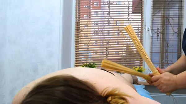 Massage therapeut maakt een anti-cellulitis massage aan een dikke vrouw op een massagetafel in een spa met een bamboe stick. Spa behandelingen. Gezondheid en schoonheid, voeding — Stockfoto