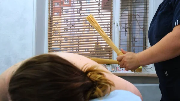Anti-cellulitis massage met bamboe sticks voor een dikke vrouw. Agressieve strijd tegen vet. Kuuroord. — Stockfoto
