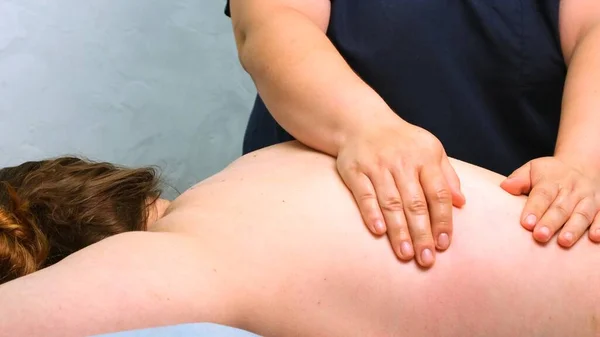 Therapeutische rugmassage. Massagetherapeut die een vrouw masseert. Lichaamsverzorging — Stockfoto