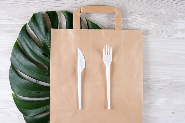 plastic fork, knife on paper bag. Eco-friendly food packaging and cotton eco bags on gray background with copy space. Carering of nature and recycling concept. containers for catering and street fast