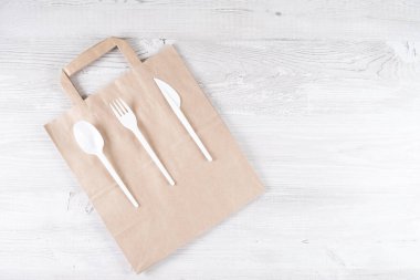 Plastik çatal, kaşık, kesekağıdındaki bıçak. Çevre dostu gıda ambalajları ve gri arka planda fotokopi alanı olan pamuk eko torbaları. Doğanın işleyişi ve geri dönüşüm konsepti. Yemek konteynırları ve...