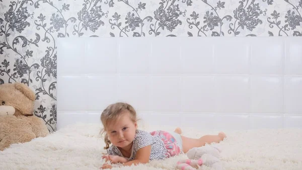 Menina feliz pulando e jogando na cama branca. — Fotografia de Stock