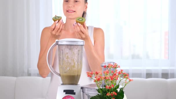 Jovem feliz preparando delicioso smoothie nutritivo no liquidificador kiwi — Vídeo de Stock