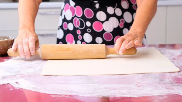 Готовить тесто со скалкой на столе. Работаю в пекарне. Бабушка готовит на кухне тесто из муки, концепцию питания, диеты и биографии. — стоковое фото