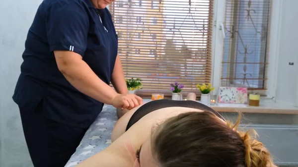 De massage therapeut voert anti-cellulitis massage van het lichaam van een dikke vrouw. Behandeling van overgewicht. — Stockfoto