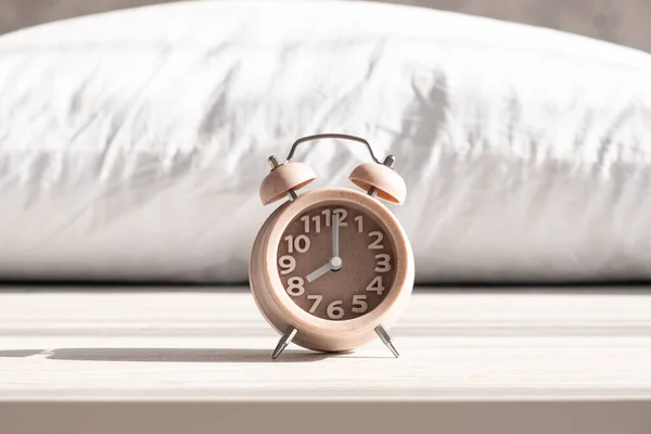 Relógio despertador fica no travesseiro na luz solar da manhã, manhã acordar hora, tempo de sono, sono saudável — Fotografia de Stock