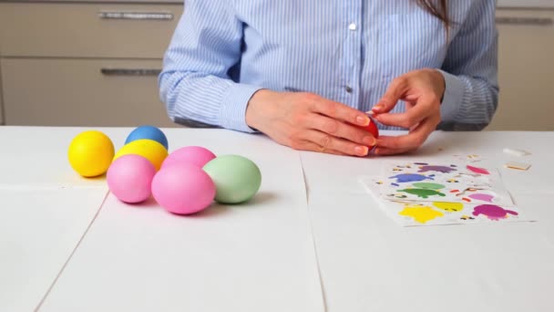 Vrouwelijke handen schildert eieren in pastelkleuren voor Pasen en versiert met vogels in het decor, zittend aan een tafel in de keuken of in een kunststudio, kopieert ruimte — Stockvideo