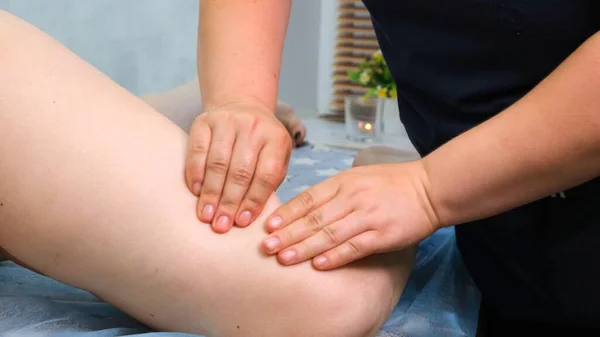 Terapeuta faz uma massagem anti-celulite. Massagista massageando pernas femininas grossas no salão de beleza. Conceito de tratamento de beleza. close-up — Fotografia de Stock