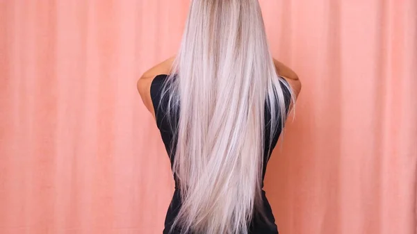 Hosszú, fényűző szőke haj egy fiatal lánytól, visszapillantással. Hajápolási koncepció. — Stock Fotó