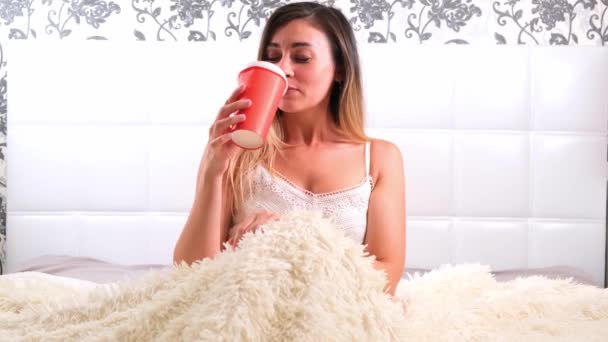 Funny female sitting in bed with takeaway coffee, enjoying the morning and drinking coffee. The concept of starting a new day, relaxing on the weekend, no need to rush anywhere, good morning — Stock Video