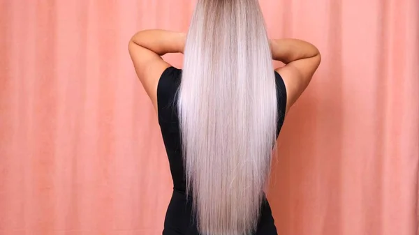 Beautiful female long straight blond hair. Dyed wavy white blond hair background, dyeing, extensions, treatment, treatment concept. Hair care. Slow motion 4K UHD video