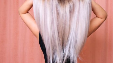 Güzel bir kadın, uzun düz sarı saçlar. Boyalı dalgalı beyaz saçlar, boyama, uzatma, tedavi konsepti. 