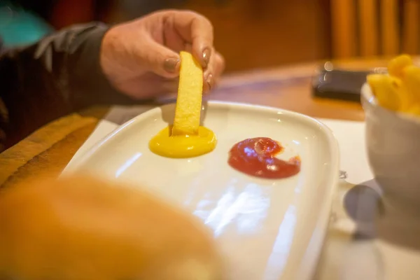 hardal ve ketçap üzerine patates cipsi koyarak kadın elleri