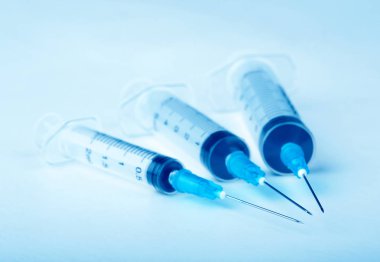 Mavi arka plan üzerinde üç plastik şırınga