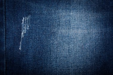 Delik desenli arka planı olan yırtık mavi kot pantolon