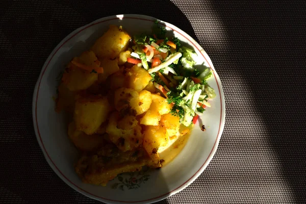 Bir tabakta duran kızarmış patatesler bir güneş ışınıyla aydınlatılır.. — Stok fotoğraf